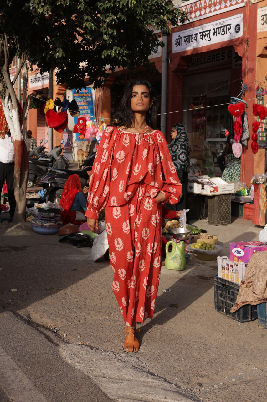 Ria Blouse Ruby Red — outdoor artisan scene, model in ruby red hand block print cotton blouse at traditional dyeing and printing workshop, Sanganer Jaipur India | Daughters of India