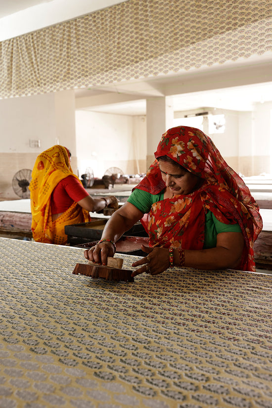 Indian women artisans hand block printing the Meadow floral pattern used in Daughters of India Bhoomi Dress, using traditional carved wooden blocks in their workshop