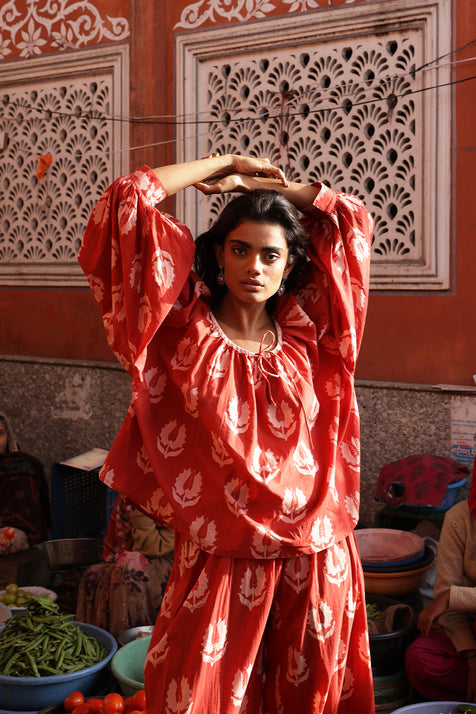 Ria Blouse Ruby Red — lifestyle Indian market portrait, model wearing ruby red hand block print cotton blouse among colourful bazaar produce and spices, artisan Jaipur India | Daughters of India